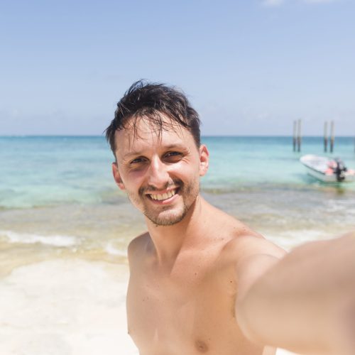 hombre-joven-alegre-tomando-selfie-en-la-playa